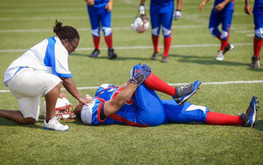 Football player lying on the floor holding his knee